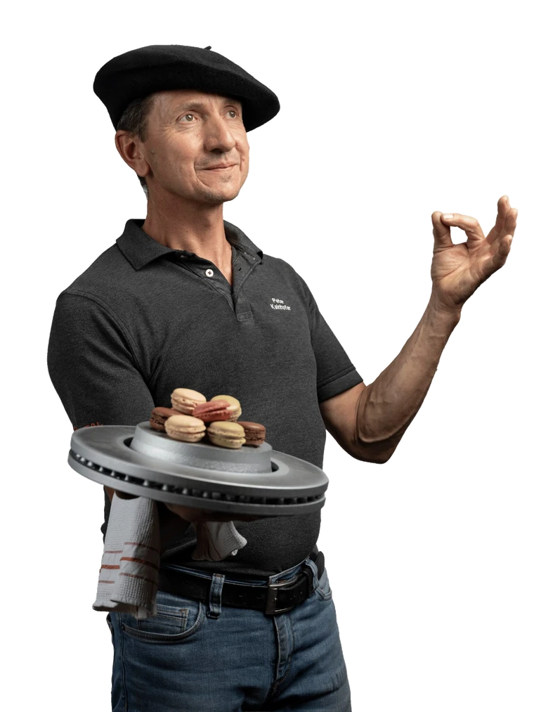 Mechaniker mit Baskenmütze serviert Macarons auf einer Bremsscheibe